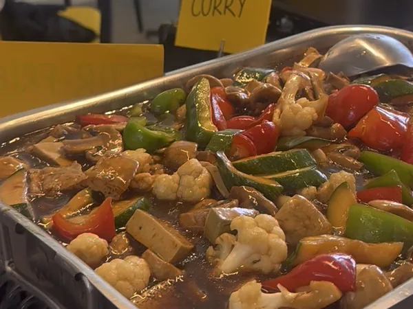 Un grand bac de légumes sautés sur son réchaud : poivrons, chou-fleur, champignons.