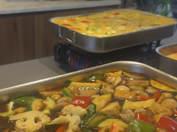 Deux plats chauds sur leurs réchauds : un curry et des légumes en sauce.