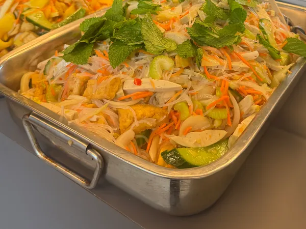 Un grand plat de salade de vermicelles, carottes, concombre et menthe.